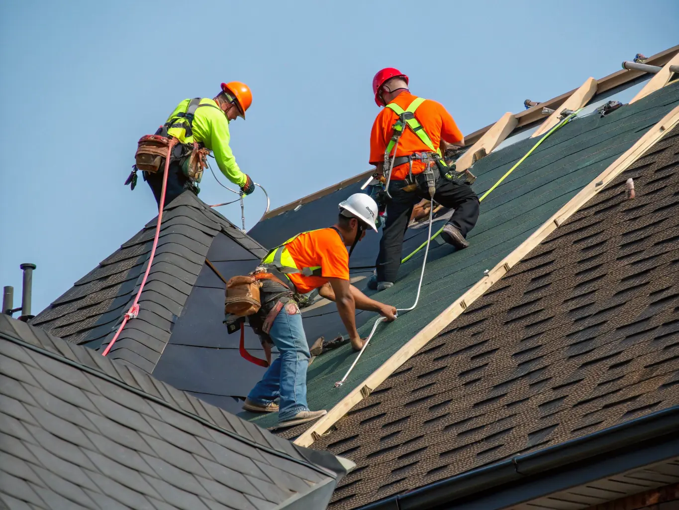 A high-angle shot of a Gomez Roofing crew expertly installing asphalt shingles on a residential roof, showcasing their attention to detail and quality workmanship.